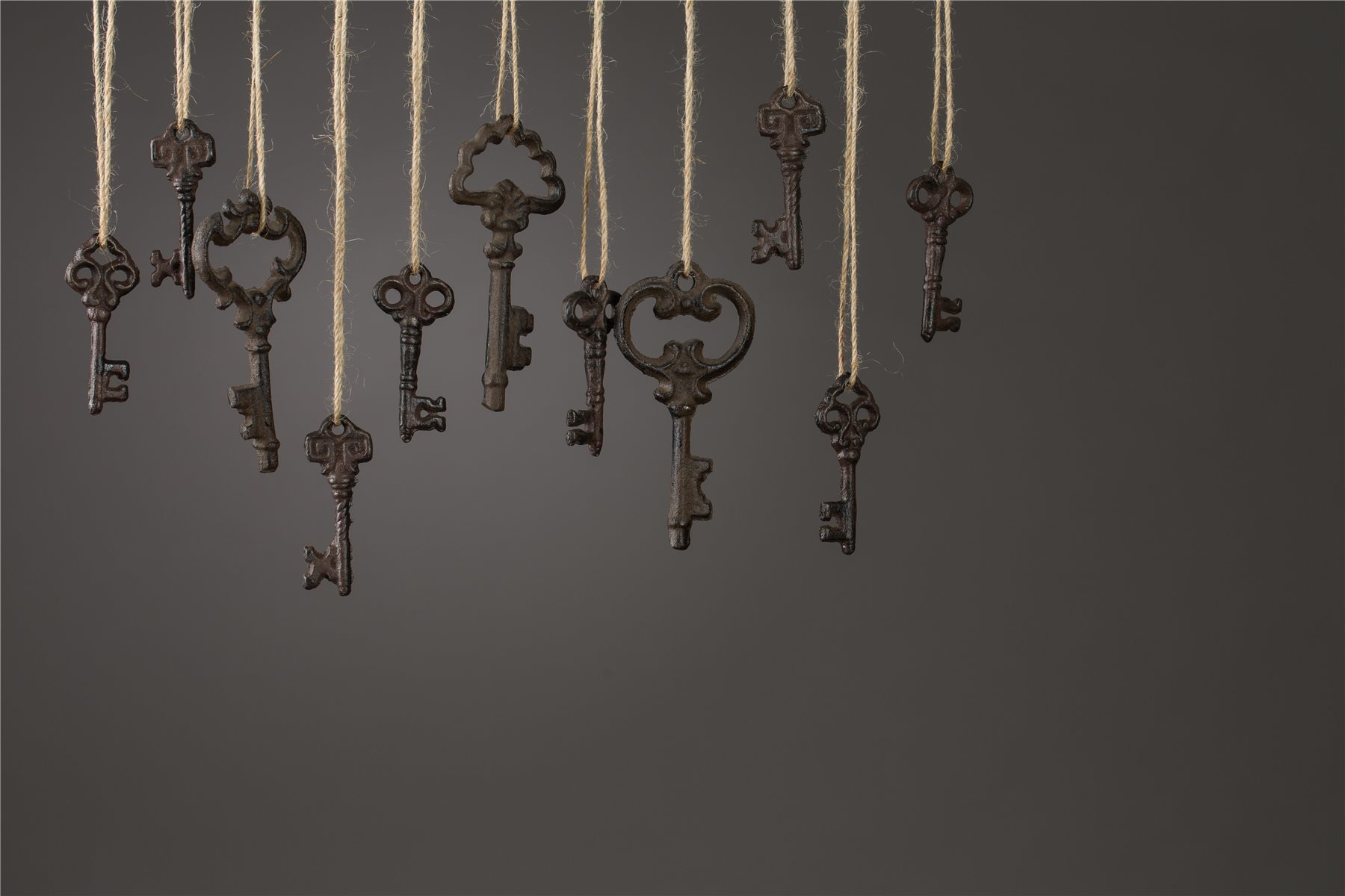 Clés anciennes en laiton suspendues sur fond sombre, ambiance d'atelier de serrurier à Caluire-et-Cuire